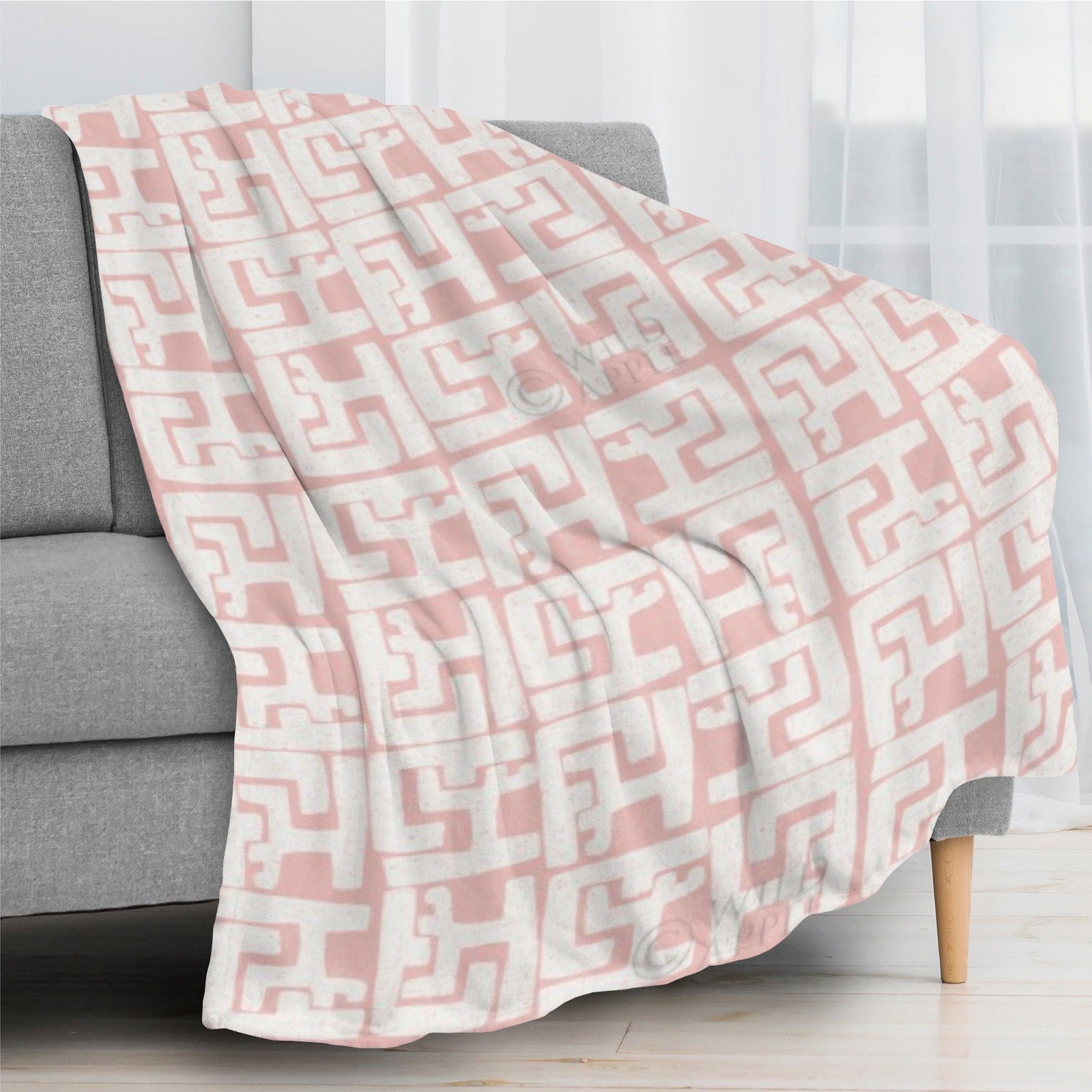 Blush pink geometric flannel blanket draped over sofa, cozy home decor