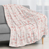 Blush pink geometric flannel blanket draped over sofa, cozy home decor