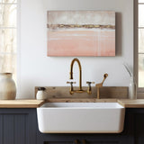 Abstract canvas wall art in pink and gold above a white farmhouse sink. Modern kitchen decor.