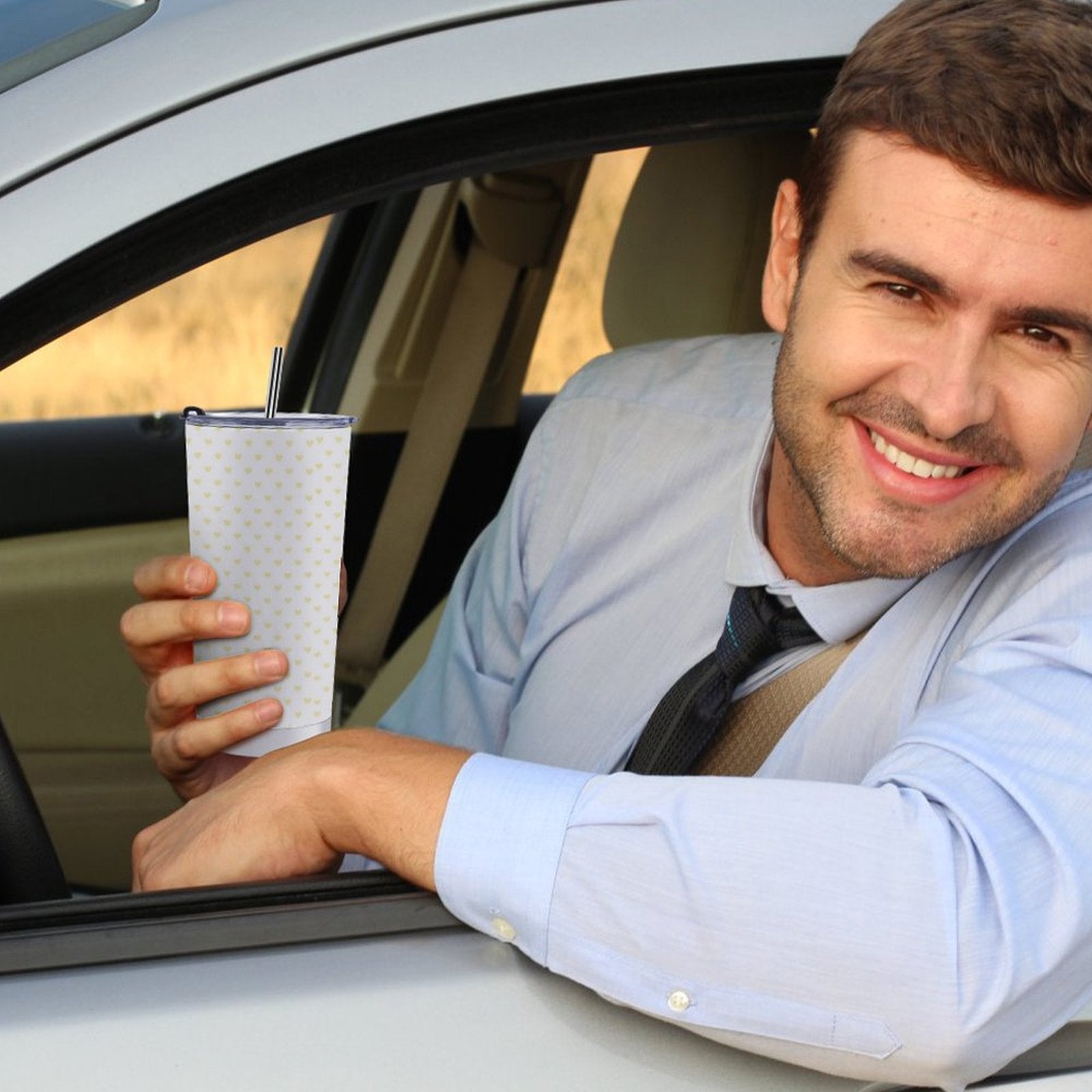 Man in car holding a personalized 20oz travel coffee tumbler with heart pattern and straw