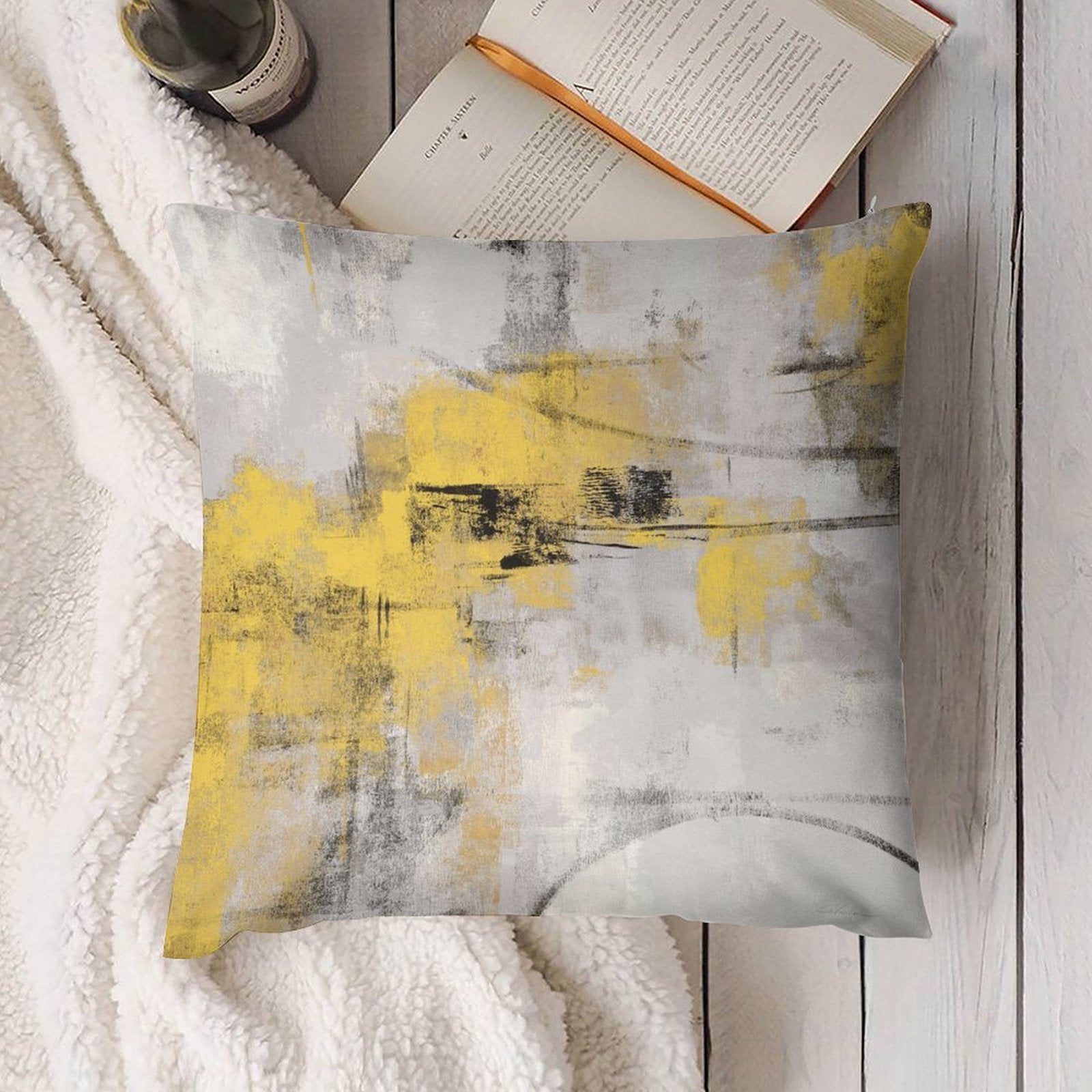 Abstract art pillow cover in yellow, gray, and black on a fluffy white blanket, living room decor