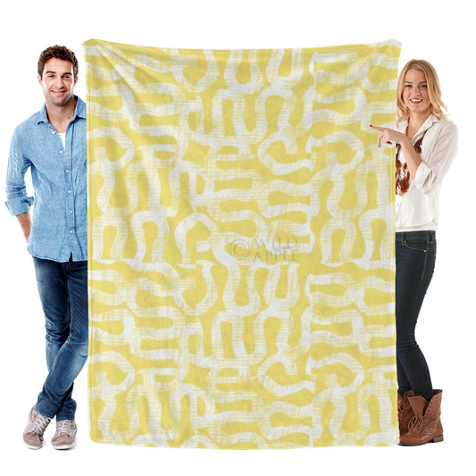 Yellow flannel blanket with white abstract pattern held by a man and woman; Made in USA