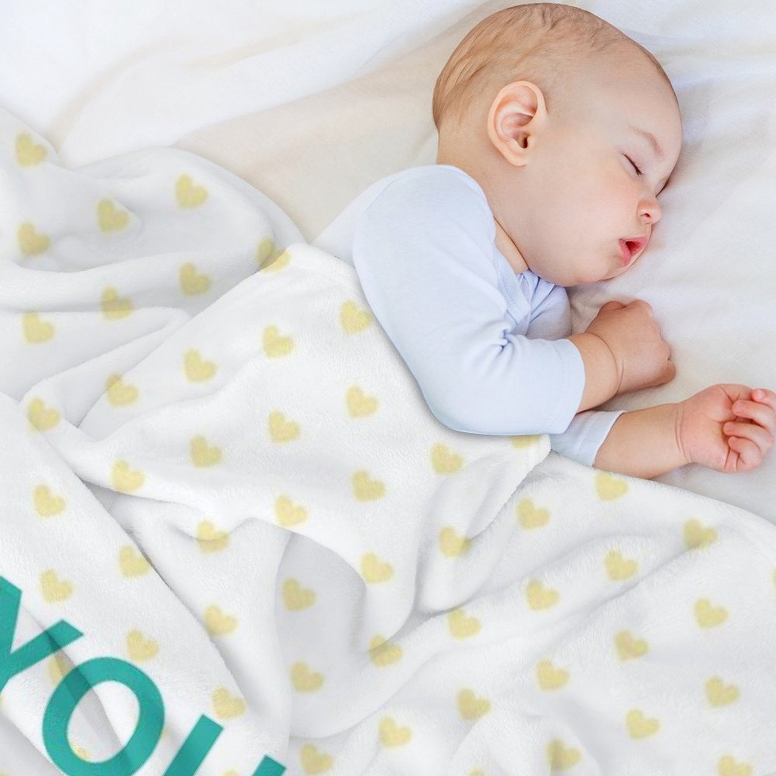 Baby sleeping on a white blanket with yellow heart pattern, cozy fleece blanket.