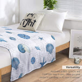 Navy shells pattern fleece blanket on bed, versatile for couch and camping, soft and warm.