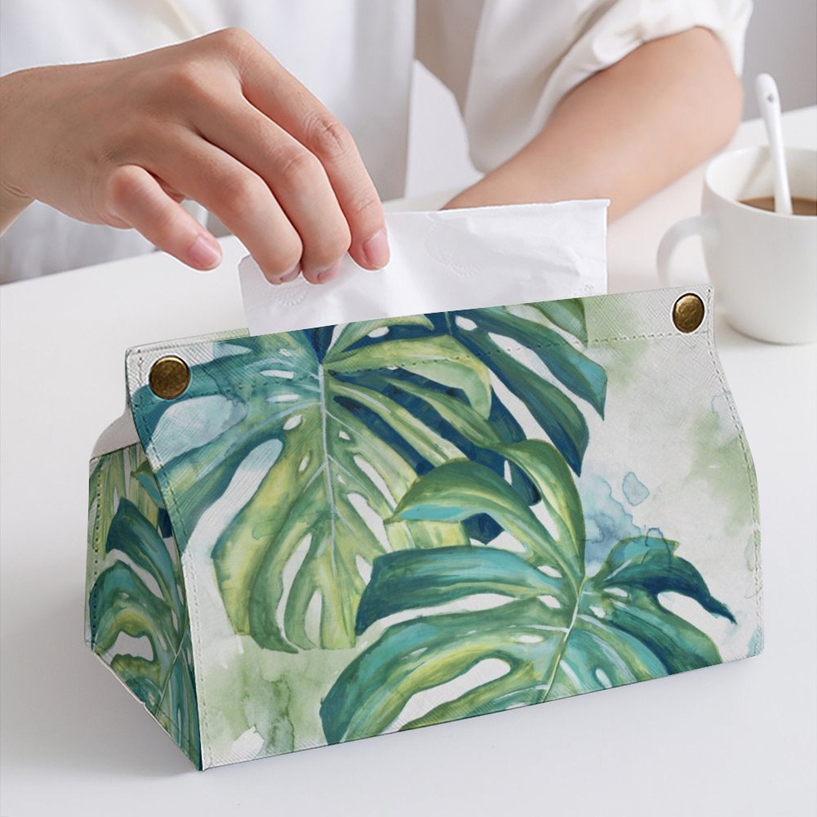 PU tissue box cover with monstera leaf design, person taking a tissue. Stylish tissue holder for home or office.