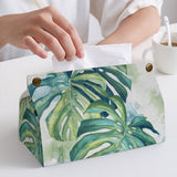 PU tissue box cover with monstera leaf design, person taking a tissue. Stylish tissue holder for home or office.