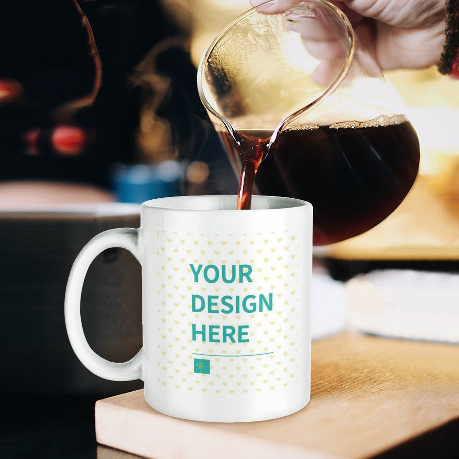 Customizable white ceramic mug with "YOUR DESIGN HERE" design being filled with coffee, perfect for personalized gifts.