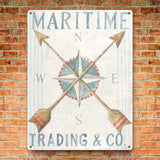 Nautical metal sign with compass design, Maritime Trading & Co text on brick wall, ideal for home decor.