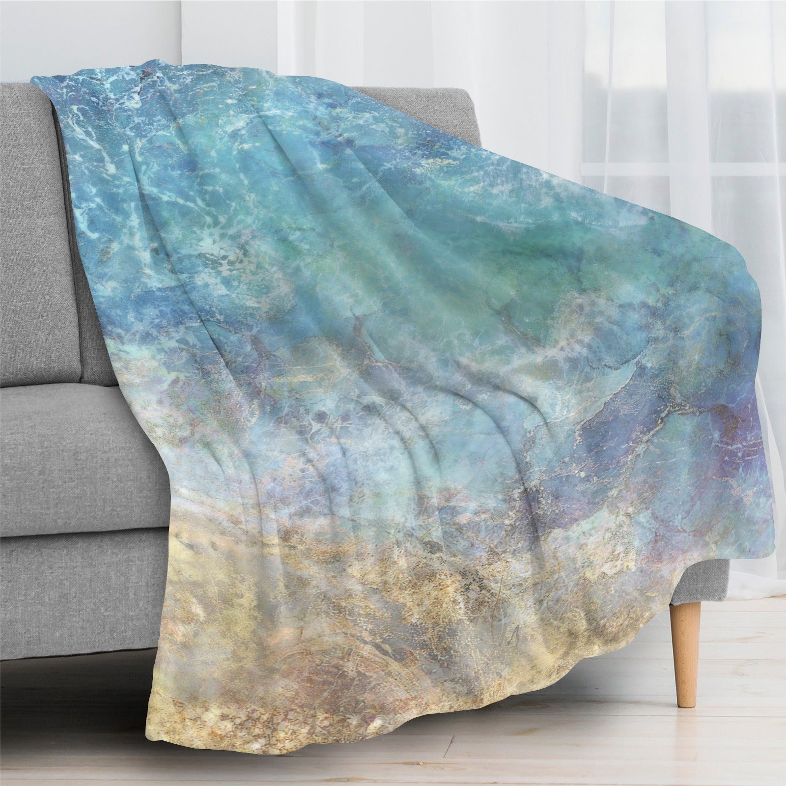 Blue ocean beach flannel blanket draped over gray sofa, wave design, for bed or couch.