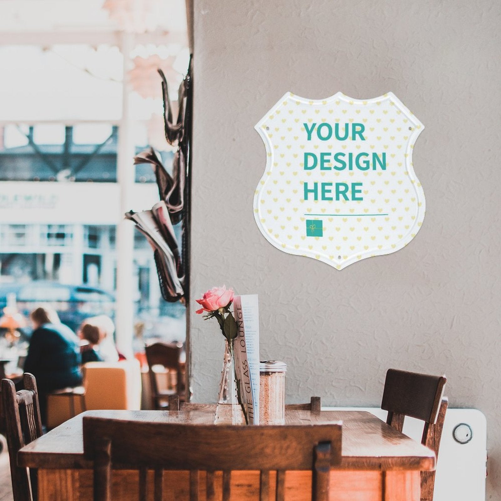 Custom shield shape metal sign on a cafe wall, featuring 'YOUR DESIGN HERE' text, ideal for cafe or shop decor