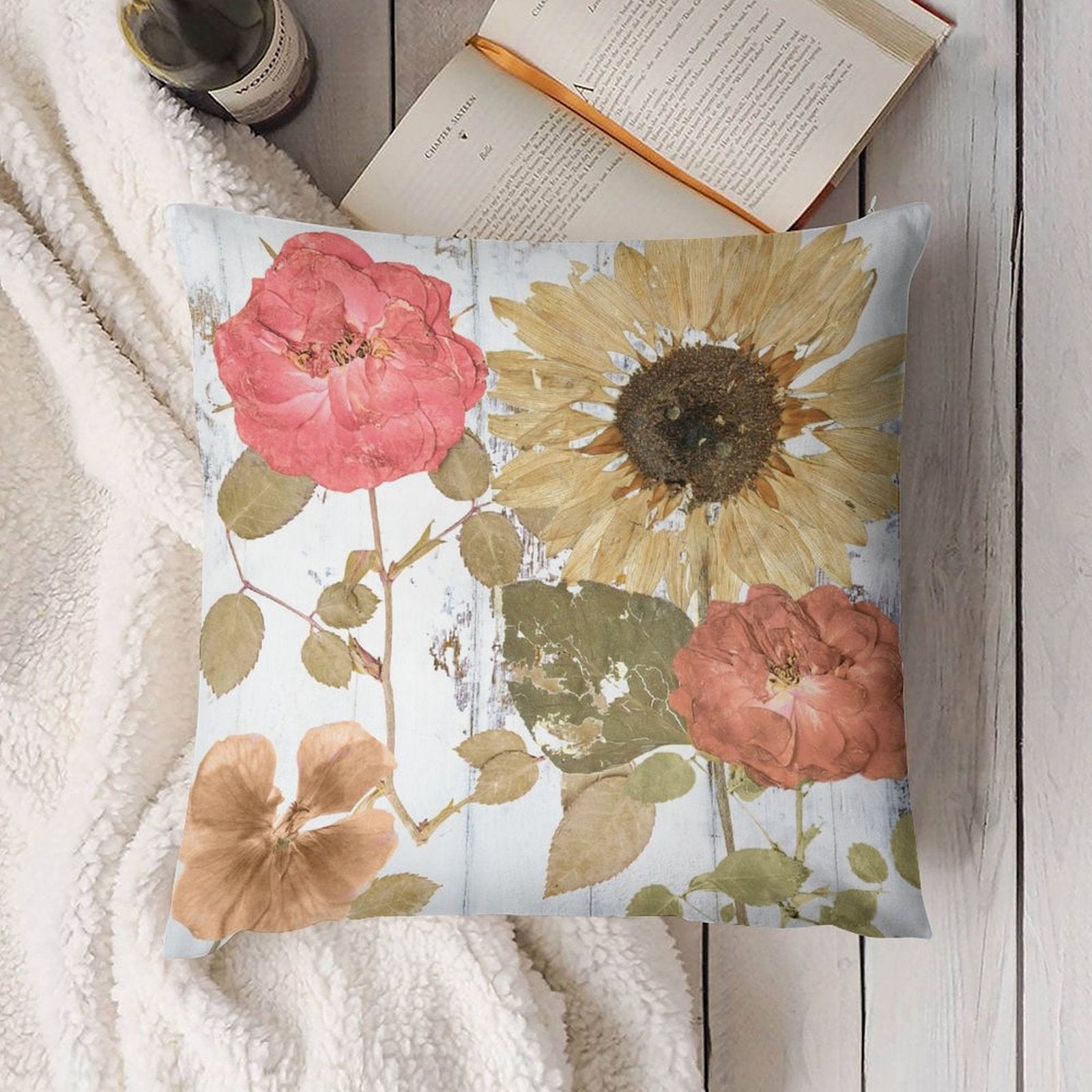 Floral throw pillow cover with rose and sunflower design on a white soft blanket.