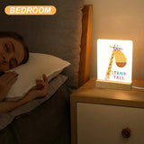 Acrylic night light with giraffe design, wooden base, and 'STAND TALL' text, ideal for bedroom decor and gifts for kids.