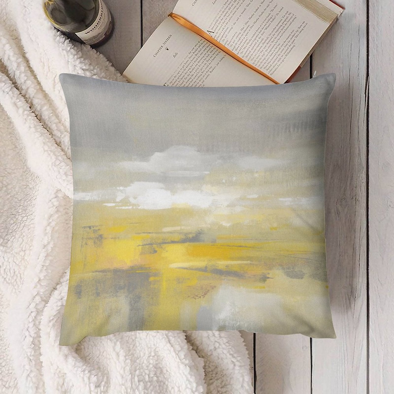 Abstract art plush pillow cover in yellow and gray, soft, for sofa or couch decor, on a white blanket and wood