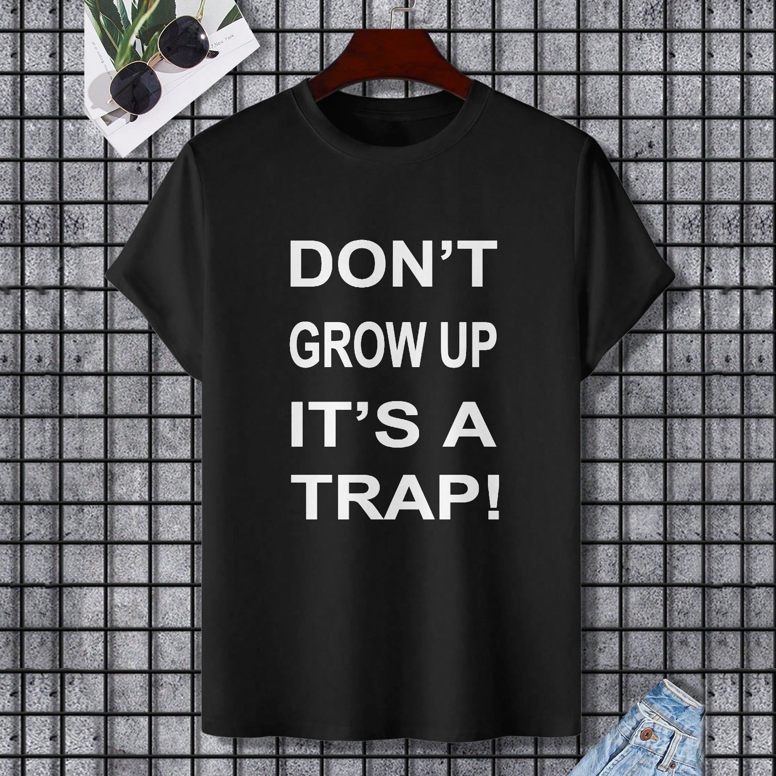Black Gildan Unisex T-shirt with "DON'T GROW UP IT'S A TRAP!" text, comfortable cotton fabric.