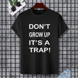 Black Gildan Unisex T-shirt with "DON'T GROW UP IT'S A TRAP!" text, comfortable cotton fabric.