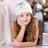 Young girl wearing a custom Christmas Santa hat with "YOUR DESIGN HERE" text; perfect for Xmas parties.