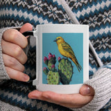 MyArtsyGift white ceramic mug with yellow bird and cactus design, black handle, and WILD APPLE art