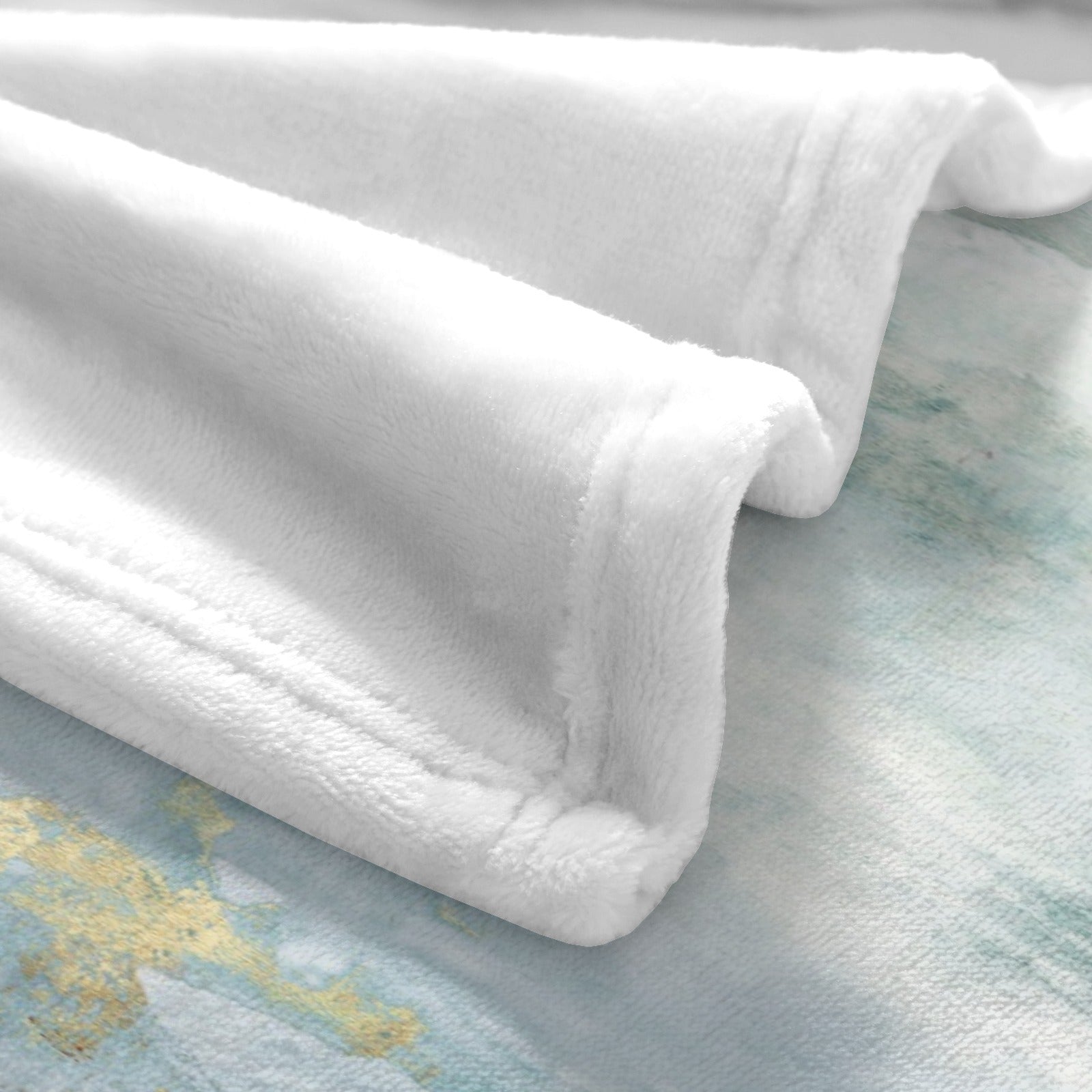 White soft flannel blanket with watercolor design on sofa or bed, perfect for cozy comfort.