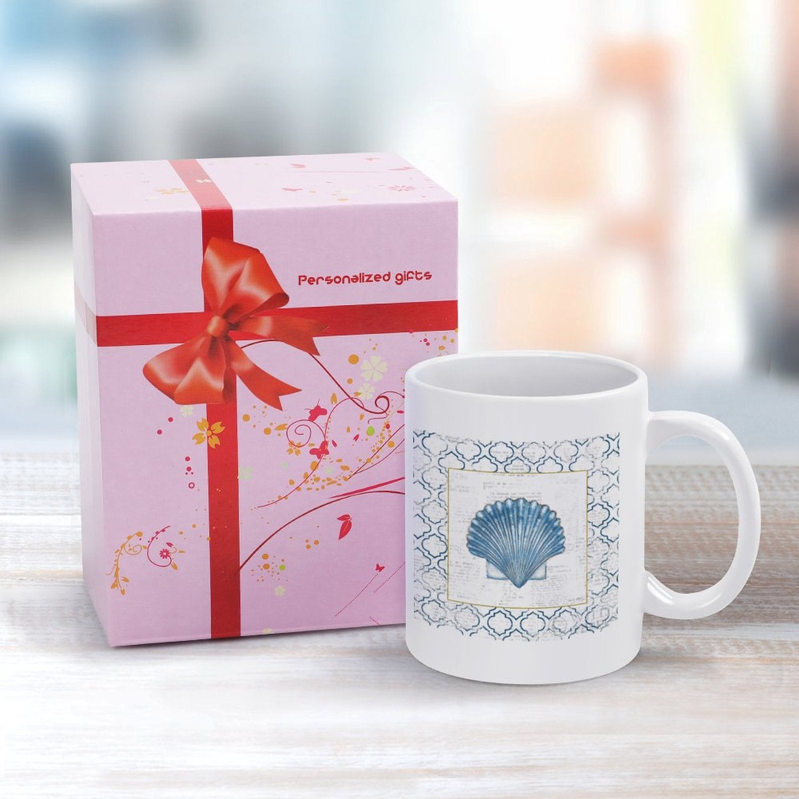 Personalized white ceramic coffee mug with blue seashell design, perfect gift.