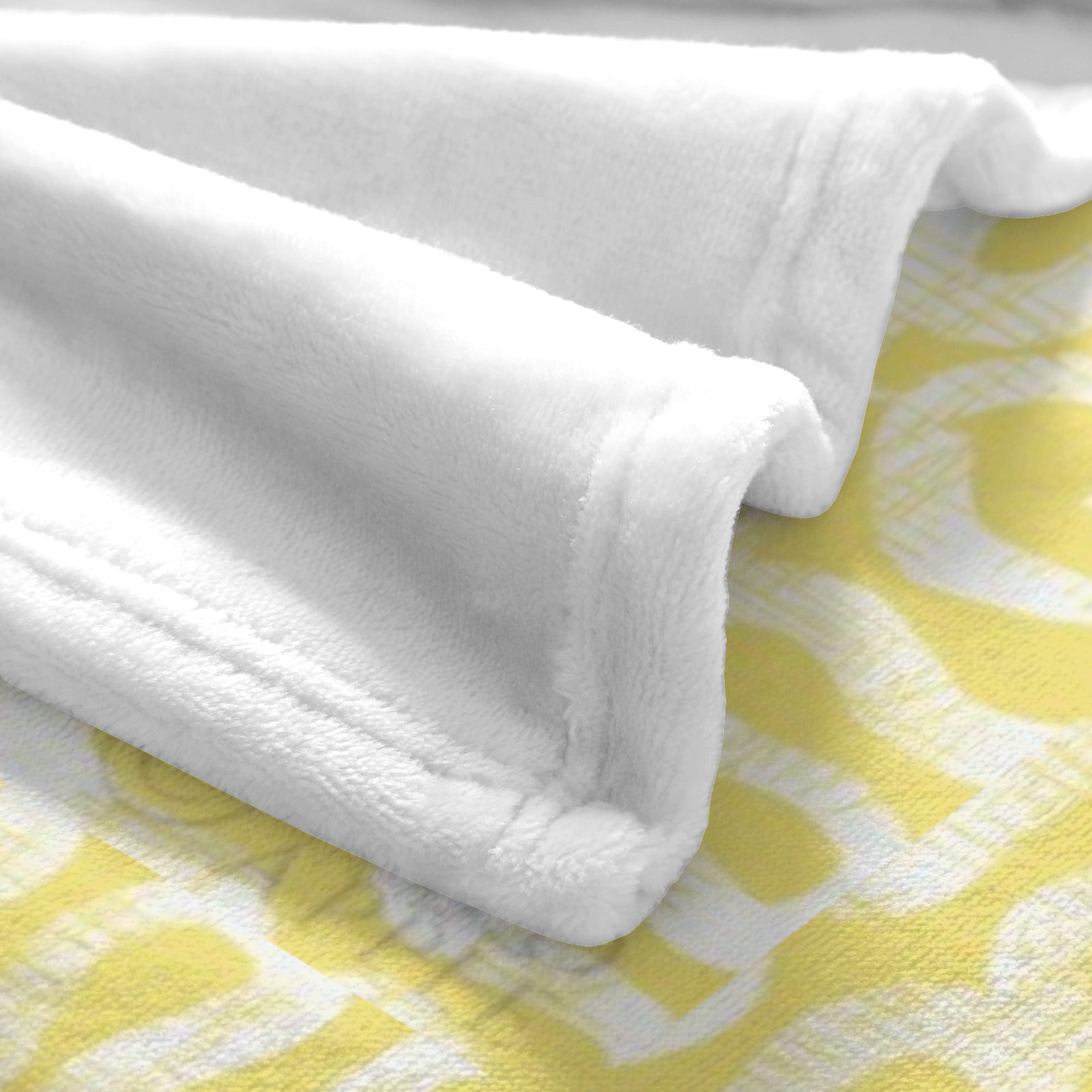 Close-up of soft white flannel blanket, yellow cross design visible, perfect for cozy home decor.