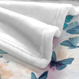 White flannel blanket corner detail with watercolor blue butterfly design.