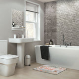 Winter-themed 'LET IT SNOW' bath rug in modern bathroom with white fixtures and gray tiles, non-slip bathroom floor carpet.