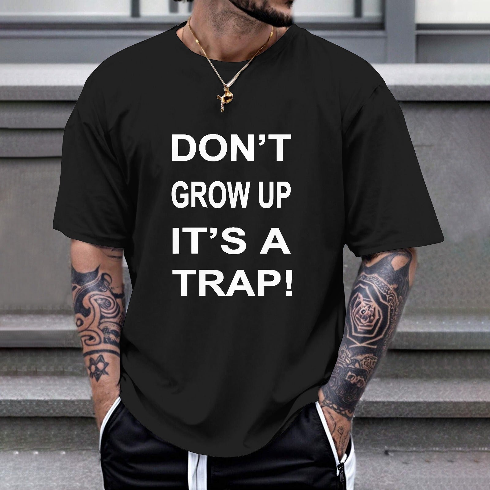 Black Gildan Unisex T-shirt with "DON'T GROW UP IT'S A TRAP!" print, comfortable cotton.