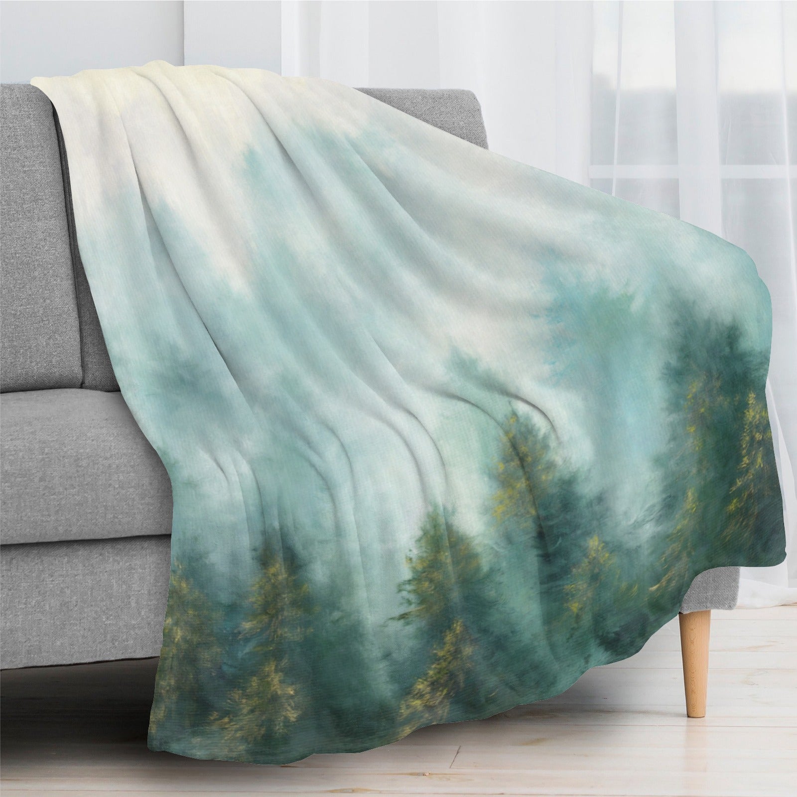 Misty forest flannel blanket on sofa. USA-made forest print, soft and cozy, perfect for indoor/outdoor use.