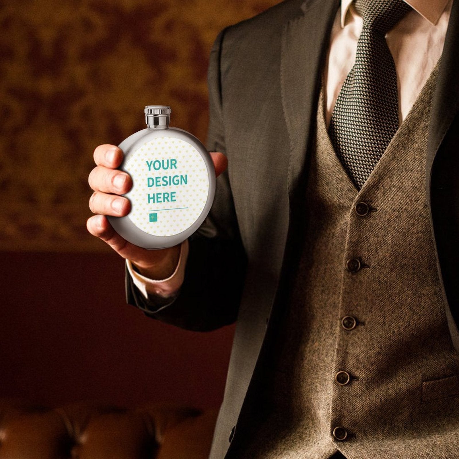 Custom stainless steel flask with "YOUR DESIGN HERE" text, held by a man in a suit, perfect personalized gift.