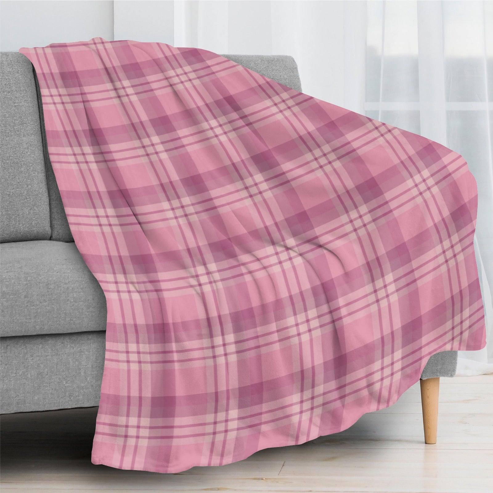 Pink buffalo plaid flannel blanket draped over a gray couch, home decor, USA made.