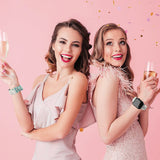 Two women wearing personalized Apple Watch bands with champagne, celebrating