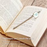 Custom metal bookmark on open book, stainless steel with design area, personalized gift for book lovers, reading accessory.