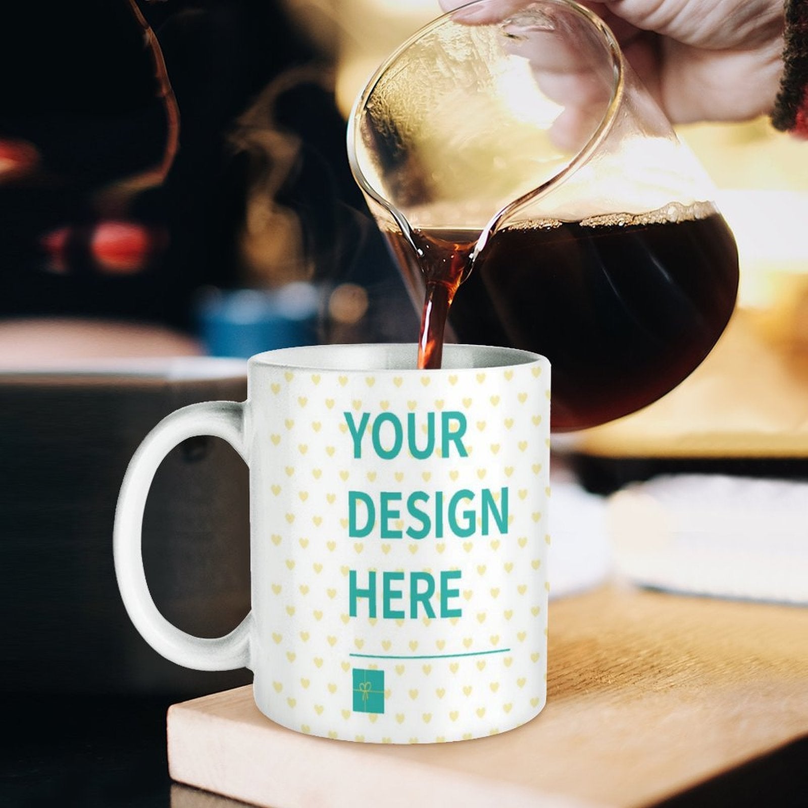Customizable white ceramic mug with "YOUR DESIGN HERE" text, perfect for a personalized gift, being filled with coffee.