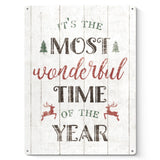Christmas metal sign with distressed look, "It's the Most Wonderful Time of the Year" on white wooden background, home decor.