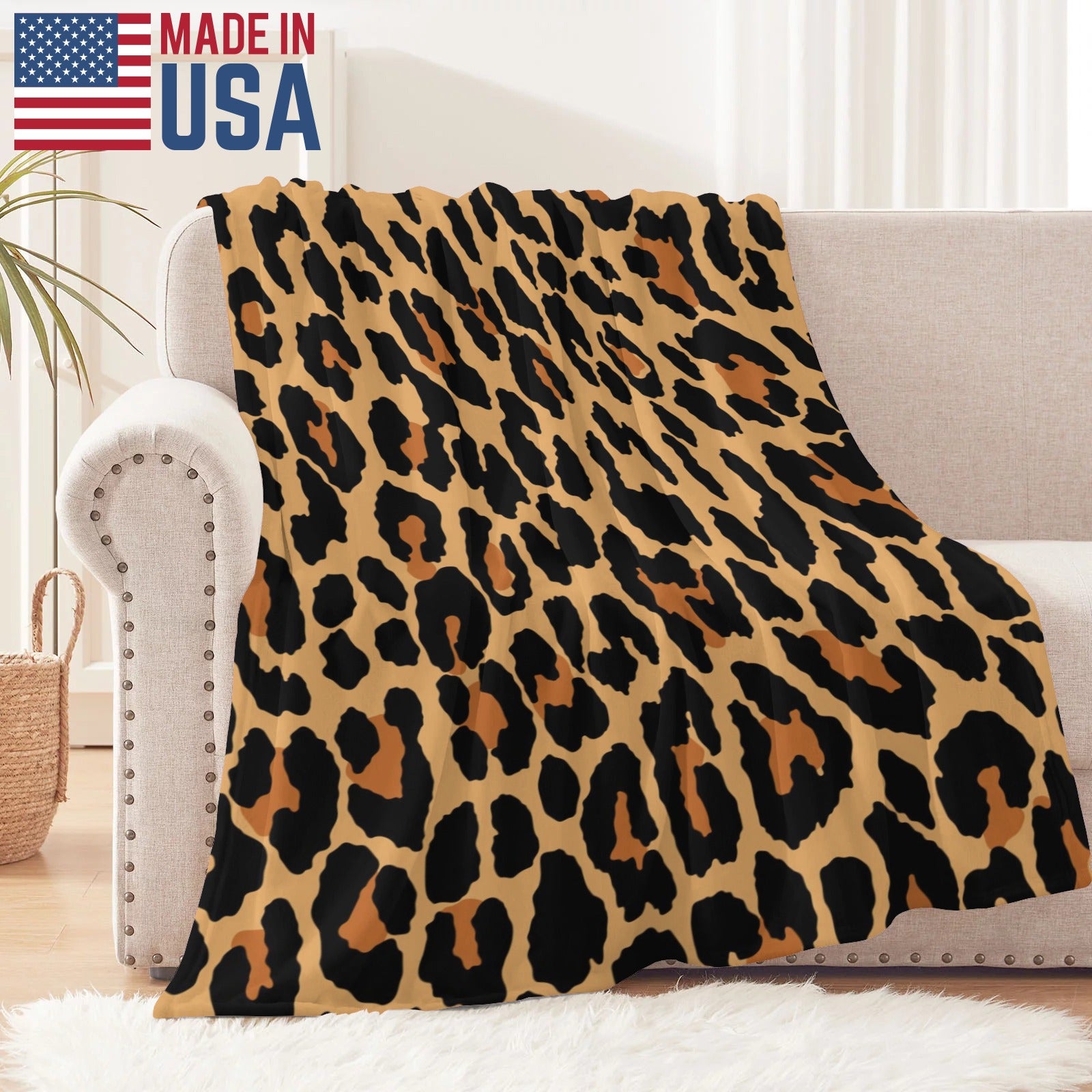 Leopard print flannel blanket, MADE IN USA, on a beige sofa. Soft, cozy, and perfect for home decor.