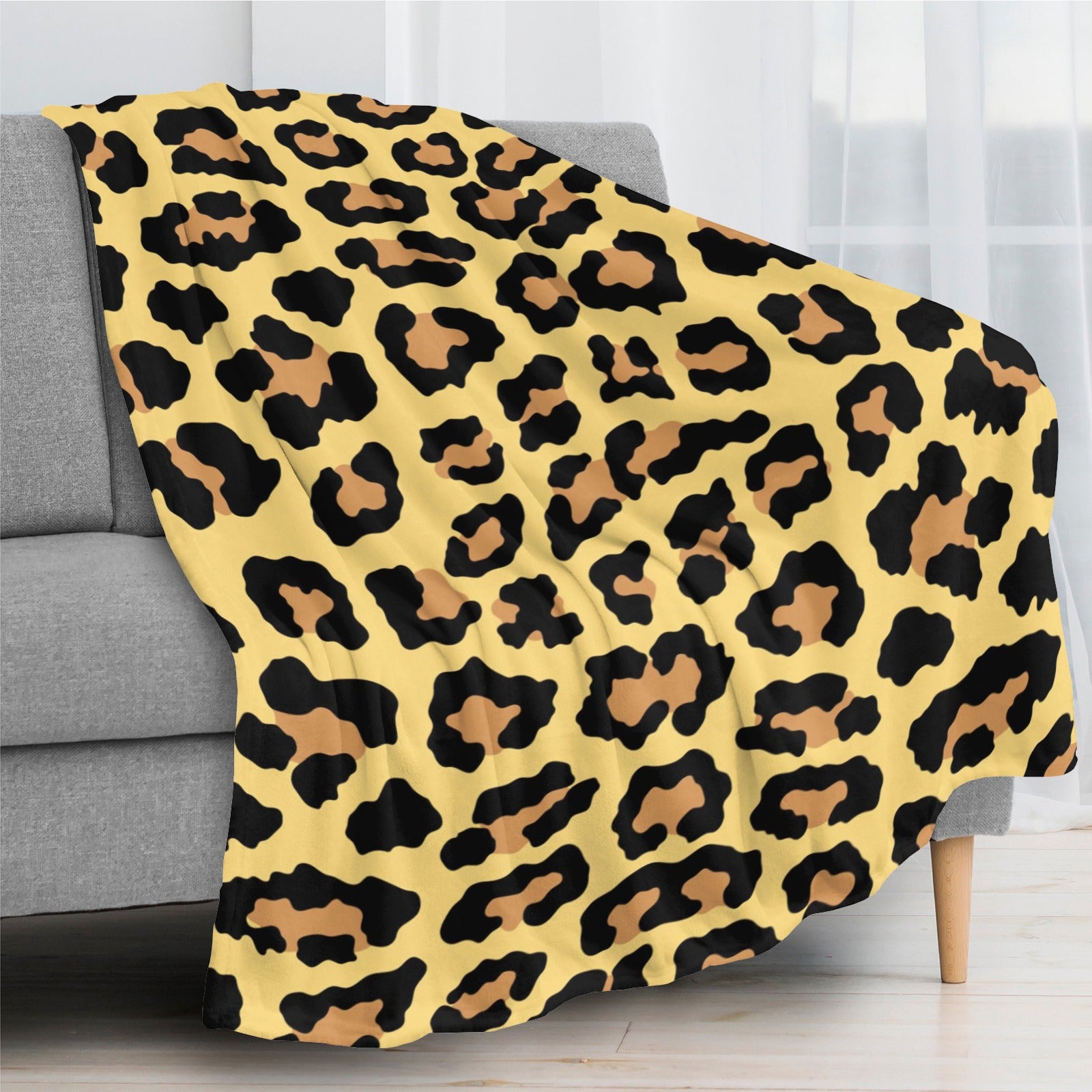 Leopard print flannel blanket on gray sofa, soft and warm, perfect for indoor and outdoor use.