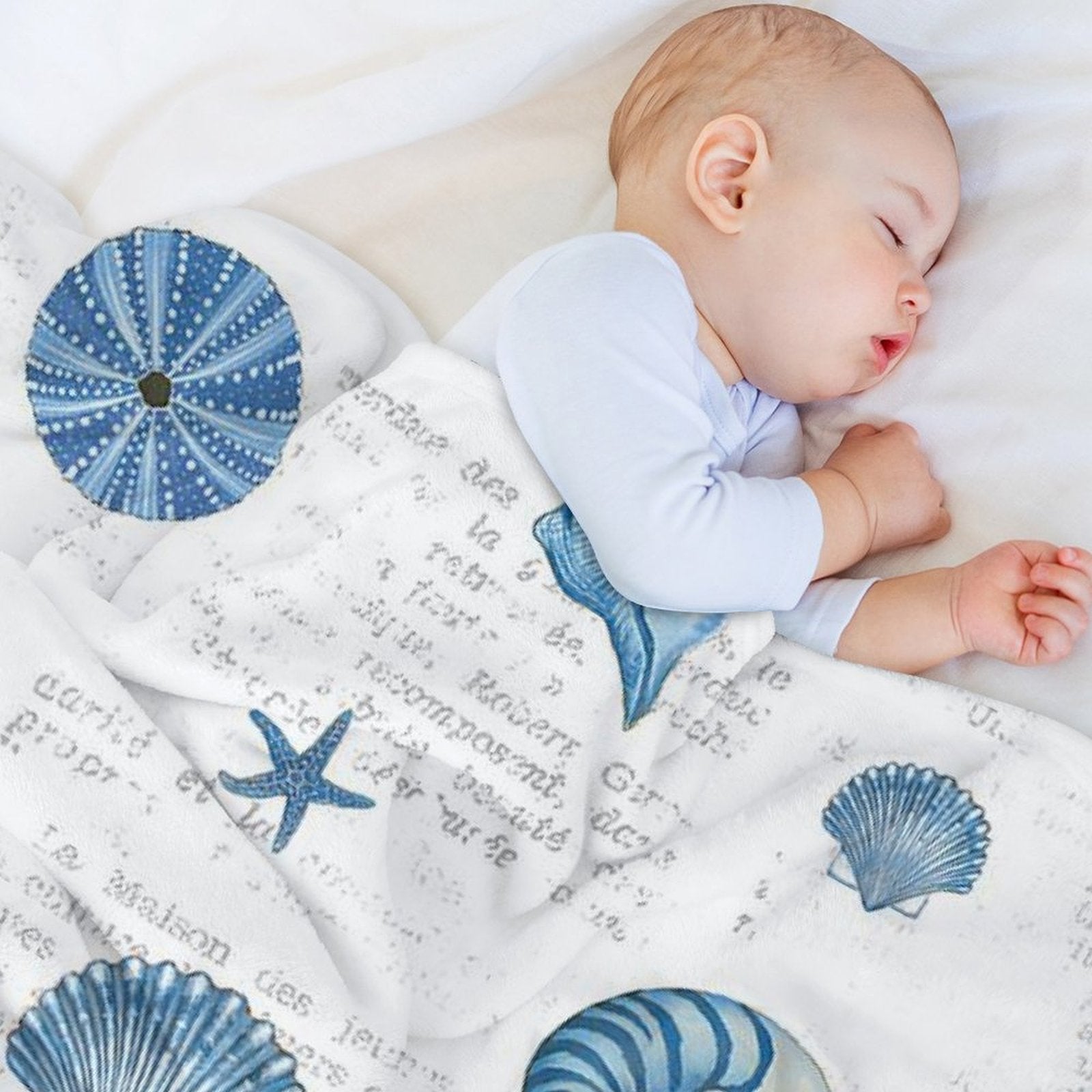 Baby sleeping on navy shells pattern fleece blanket, seashell and starfish design, cozy and soft.