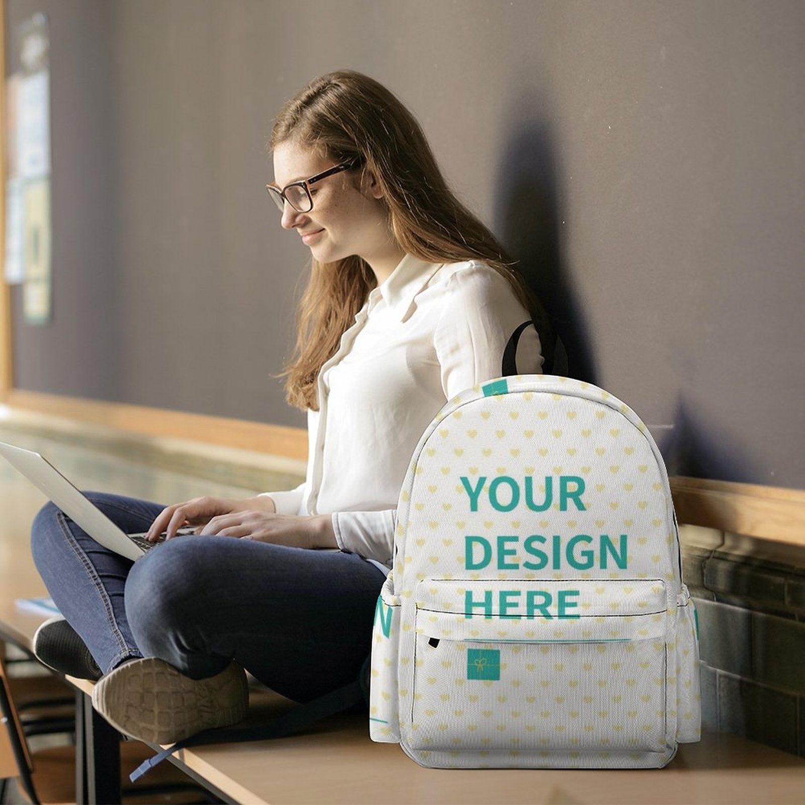 Customizable Oxford cloth backpack with 'YOUR DESIGN HERE', heart pattern, and a girl using laptop; personalized bookbag