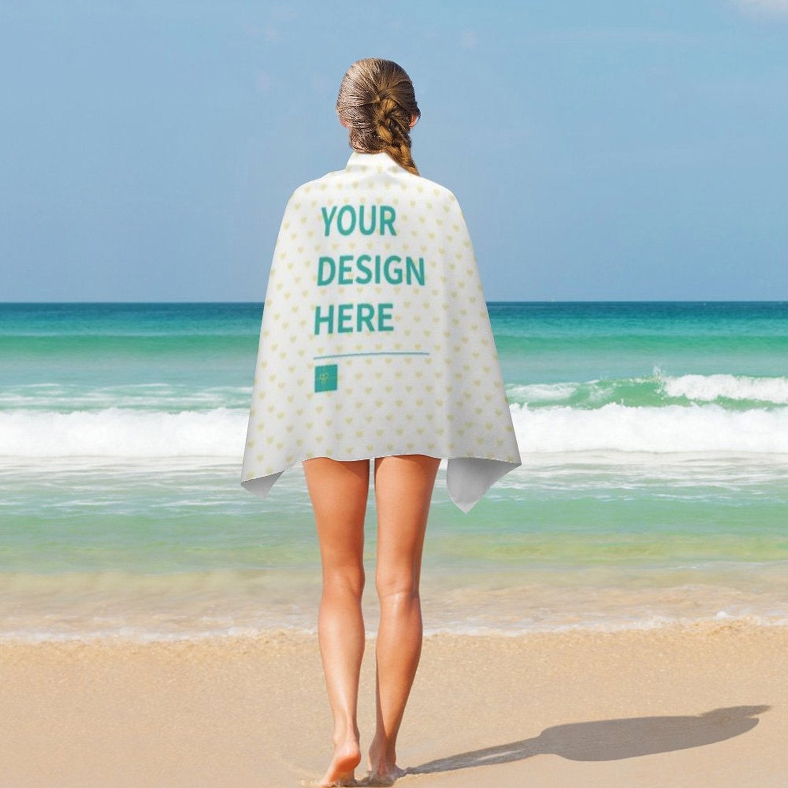 Custom beach towel, double-faced pile, personalized with 'YOUR DESIGN HERE', on a woman at the beach