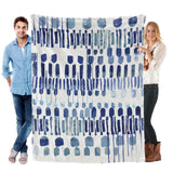 Modern blue abstract flannel blanket, held by a man and woman, cozy decor