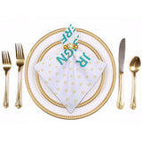 Personalized table napkin with JR text and heart pattern, part of elegant table setting with gold cutlery and plates.