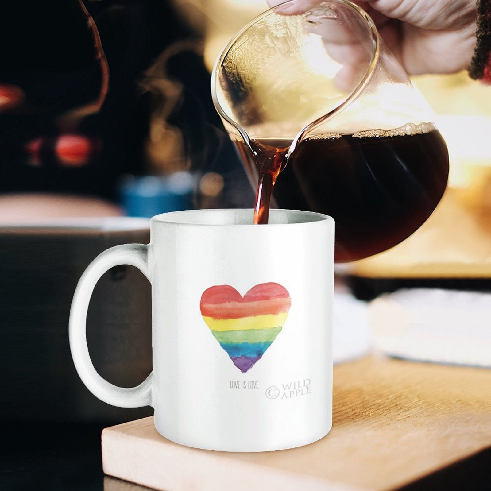 White ceramic mug with rainbow heart and "Love is Love" text, perfect Pride gift, being filled with coffee
