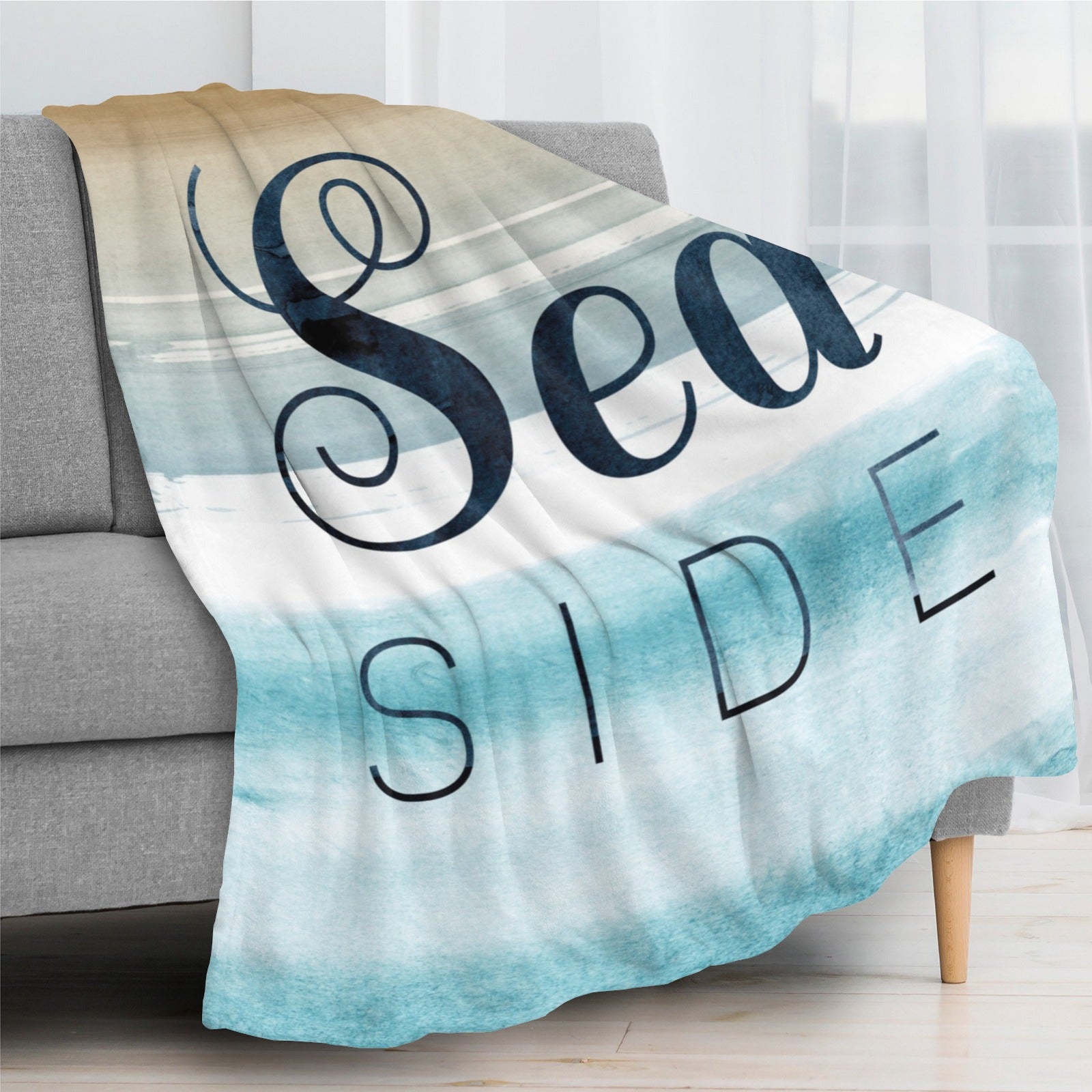 Beach Blue Seaside Flannel Blanket draped on a gray sofa, with "Sea SIDE" text design, soft and cozy