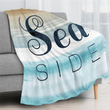 Beach Blue Seaside Flannel Blanket draped on a gray sofa, with "Sea SIDE" text design, soft and cozy